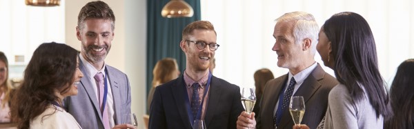 Five people networking at a conference reception. In-person networking can be a vital skill.