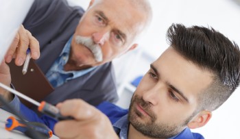 Experienced old man teaching a younger apprentice.