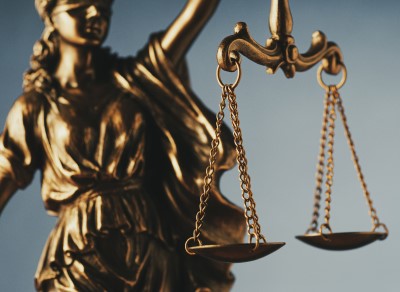Image of a golden cast of Justice, blindfolded and holding her scales aloft, with the scales being the focal point.