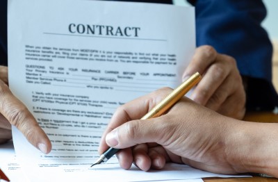 Image of a contract being signed. Your client's signature on the contract and scope of work represents that they are aware of any consequences that you hold the right to enforce.