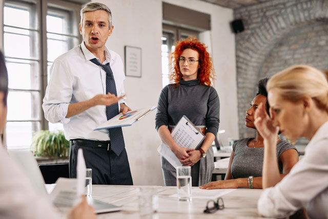 angry-businessman-feeling-disappointed-with-business-reports-scolding-his-team-meeting-office